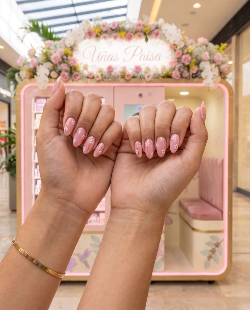 Manos con uñas rosadas recién impresas frente a la cabina